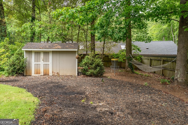 view of yard with fence, a storage unit, and an outdoor structure