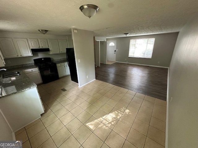 2036 Countydown Ln, Stone Mountain, GA 30088 - kitchen with black appliances, light tile patterned floors, ventilation hood, a sink, and a textured ceiling