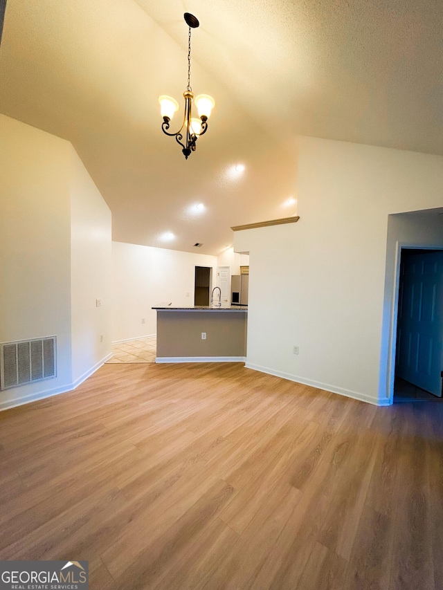 3077 Oakside Cir, Milton, GA 30004 - unfurnished living room featuring vaulted ceiling, a chandelier, and light wood-style floors