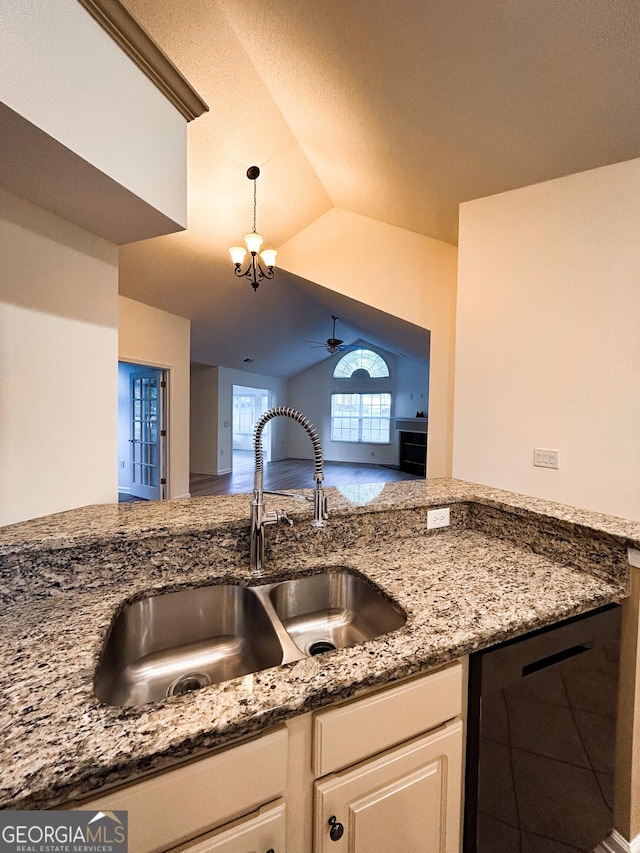 3077 Oakside Cir, Milton, GA 30004 - kitchen with light stone counters, a ceiling fan, decorative light fixtures, white cabinetry, and vaulted ceiling