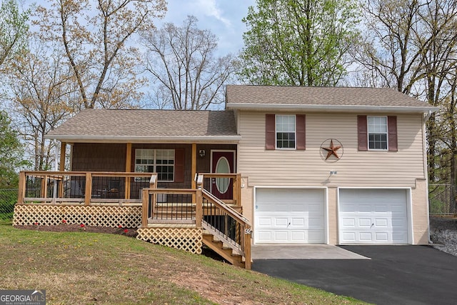 split level home featuring a porch, driveway, roof with shingles, a front yard, and an attached garage