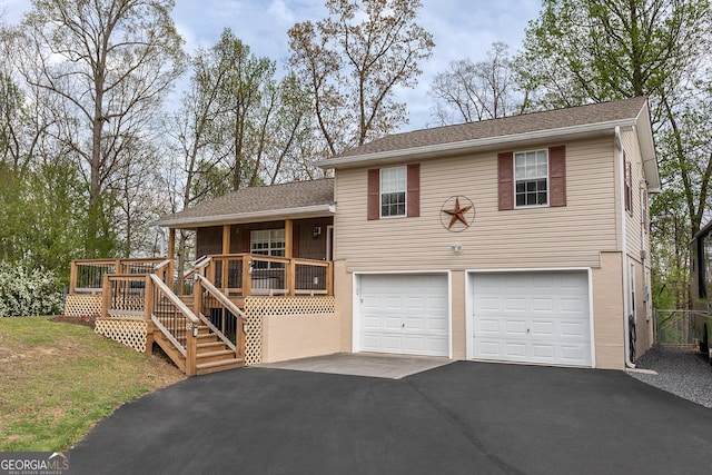 tri-level home with a garage, roof with shingles, stairway, and aphalt driveway