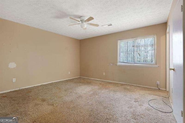 carpeted spare room featuring baseboards, a ceiling fan, and a textured ceiling