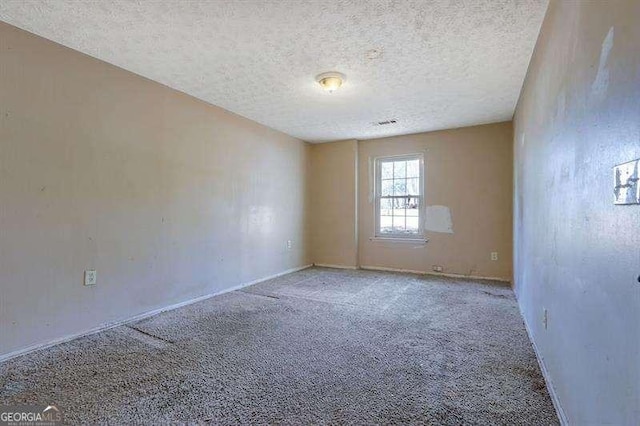 carpeted empty room featuring a textured ceiling and baseboards