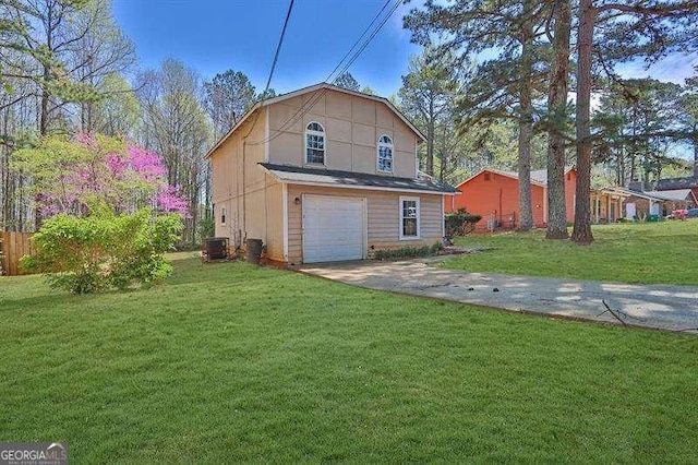 back of property featuring a yard, an attached garage, driveway, and central AC unit