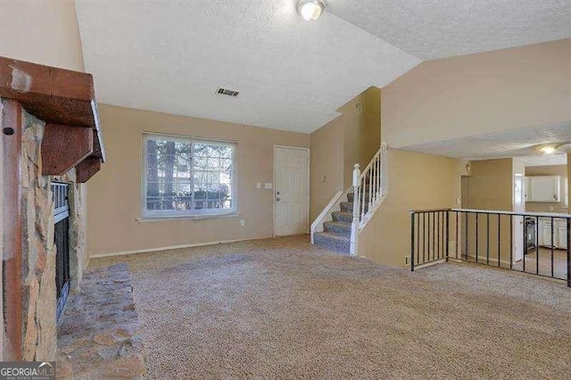 unfurnished living room with a fireplace, a textured ceiling, carpet, vaulted ceiling, and visible vents