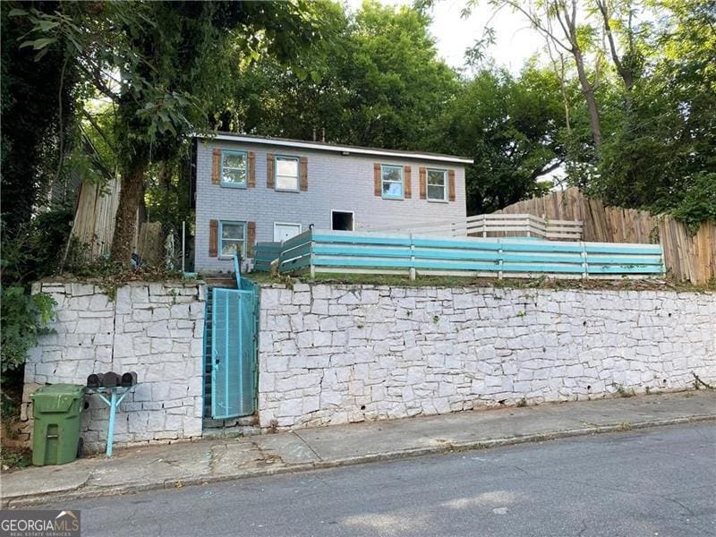 view of front of property with fence, brick siding, and a gate