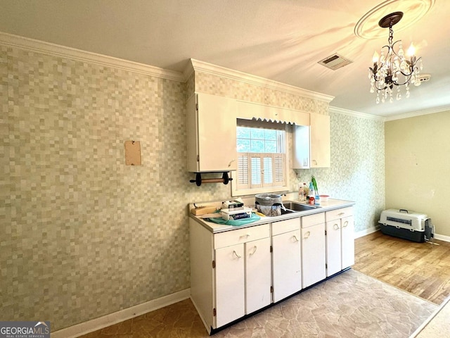 kitchen with crown molding, visible vents, an inviting chandelier, light countertops, and white cabinetry