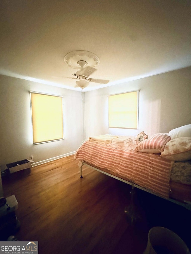 bedroom featuring baseboards, a ceiling fan, and wood finished floors