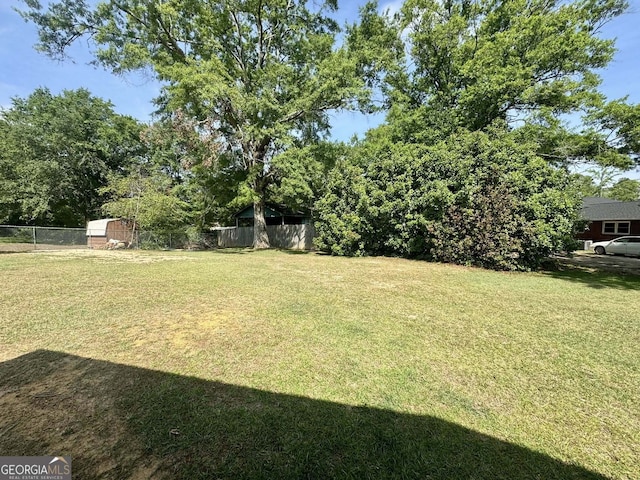 view of yard with fence, an outbuilding, and a storage unit