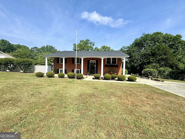 split foyer home with fence, driveway, brick siding, and a front yard