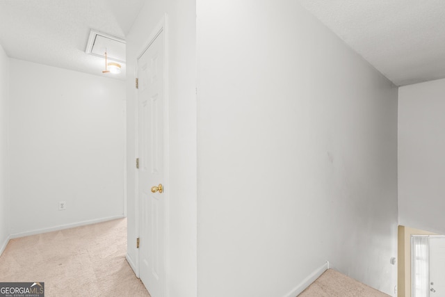 corridor featuring carpet floors, baseboards, and attic access