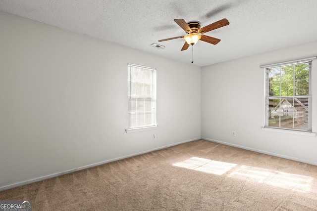 carpeted empty room with baseboards, ceiling fan, a textured ceiling, and visible vents
