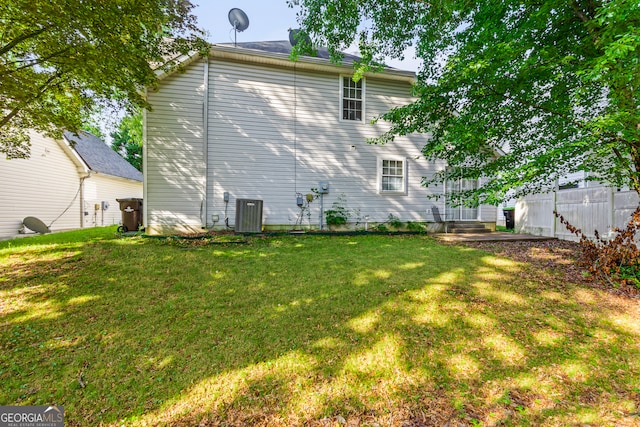 rear view of house featuring a lawn, fence, and central air condition unit