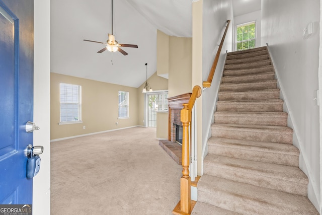 stairs with ceiling fan, a fireplace, carpet floors, high vaulted ceiling, and baseboards