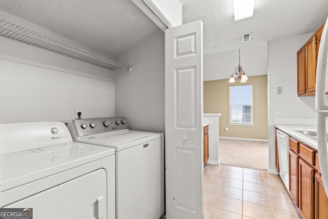 washroom with laundry area, visible vents, washing machine and dryer, light tile patterned floors, and baseboards