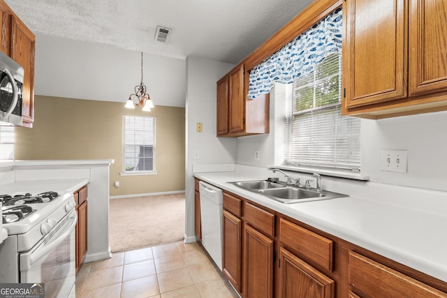 kitchen with visible vents, a sink, light countertops, a notable chandelier, and white appliances