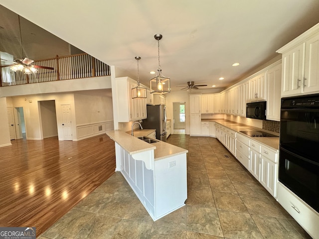 kitchen featuring a peninsula, ceiling fan, white cabinetry, a sink, and black appliances