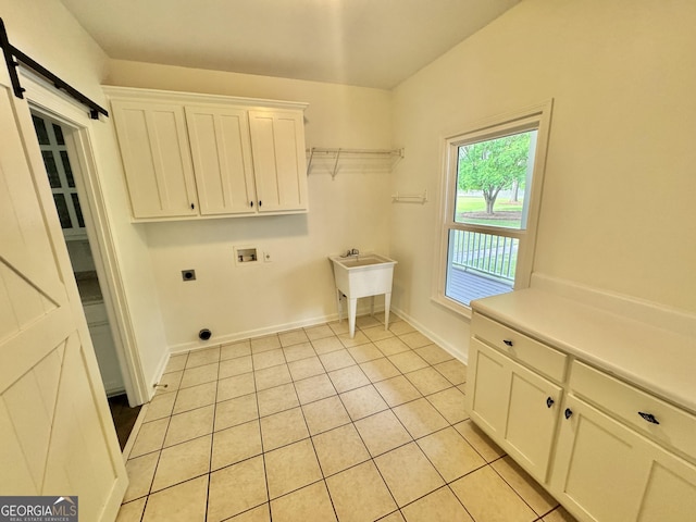 laundry area with electric dryer hookup, a barn door, cabinet space, light tile patterned floors, and hookup for a washing machine