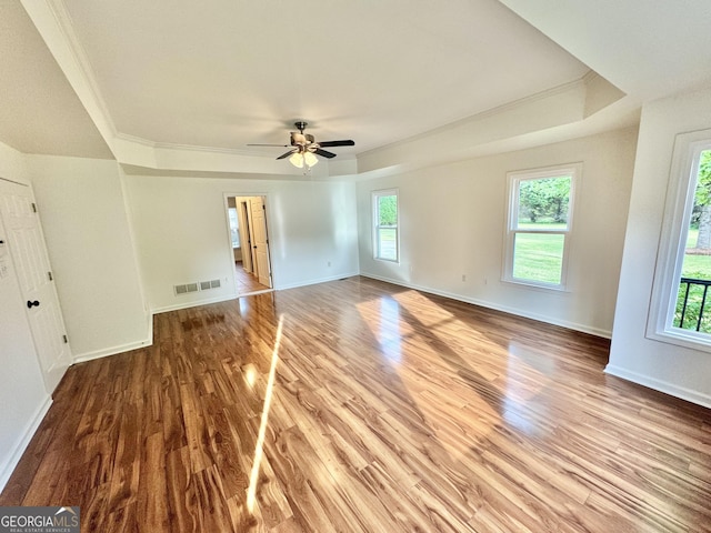interior space featuring visible vents, ornamental molding, a raised ceiling, and wood finished floors