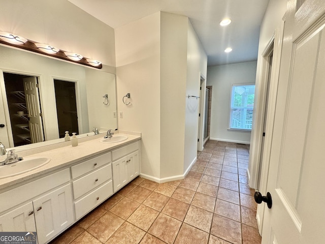 full bathroom with double vanity, a sink, baseboards, and tile patterned floors