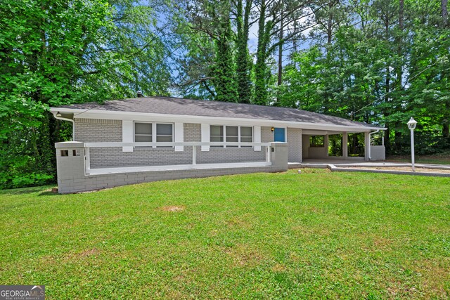 view of front facade featuring brick siding, a carport, and a front yard