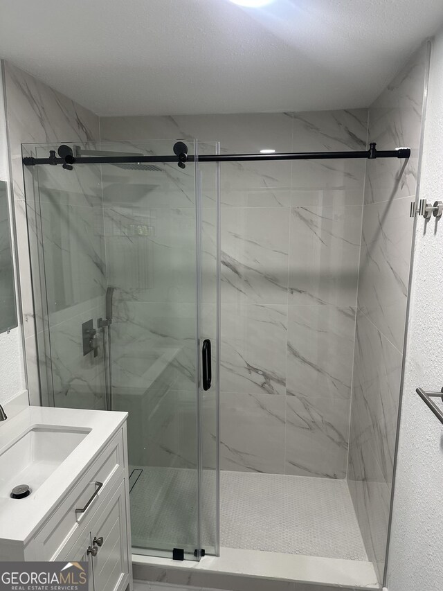 bathroom with a marble finish shower and vanity