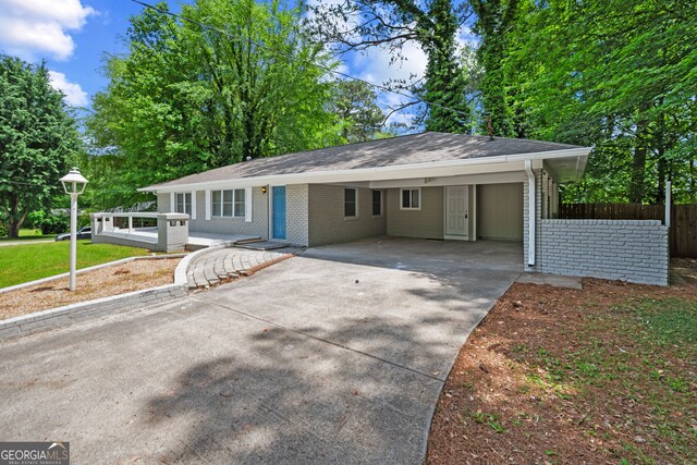 ranch-style house featuring brick siding, driveway, fence, an attached carport, and a shingled roof