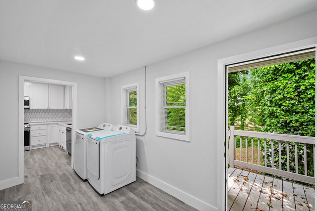 laundry area with separate washer and dryer, laundry area, light wood finished floors, and baseboards