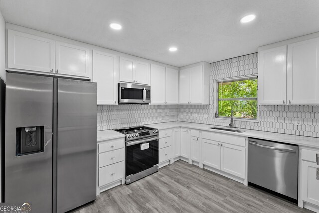 kitchen featuring light countertops, stainless steel appliances, white cabinetry, and a sink