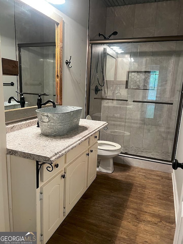 full bathroom featuring vanity, a stall shower, toilet, and wood finished floors