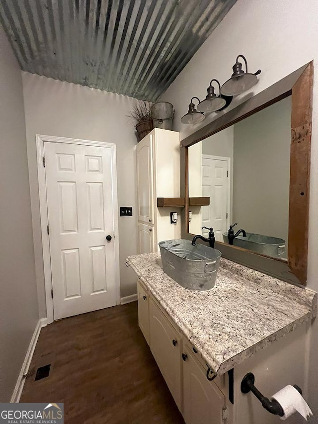 bathroom featuring baseboards, wood finished floors, visible vents, and vanity