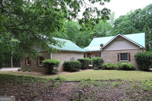 view of front facade with metal roof, a front lawn, and brick siding