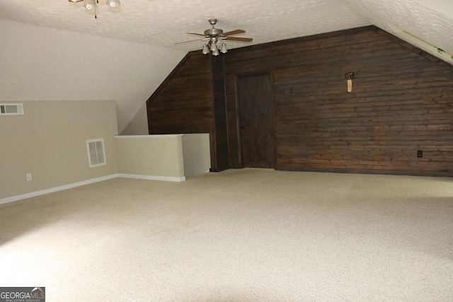 bonus room with vaulted ceiling, wood walls, and visible vents