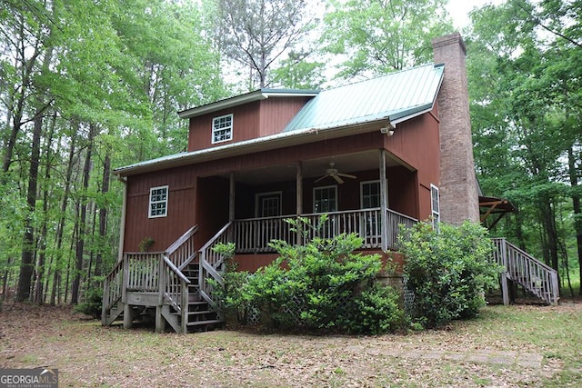 rustic home featuring ceiling fan, a porch, stairway, a chimney, and metal roof