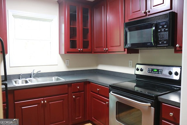 kitchen with stainless steel electric range, black microwave, dark countertops, and a sink