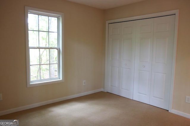 unfurnished bedroom featuring baseboards, a closet, and light colored carpet