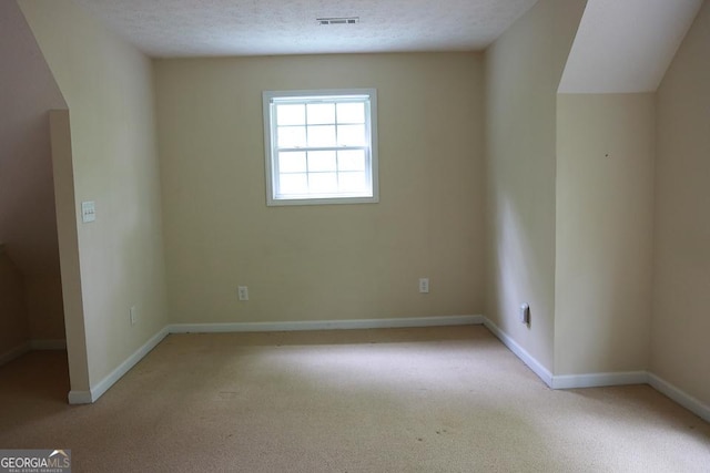 spare room featuring visible vents, baseboards, and light carpet