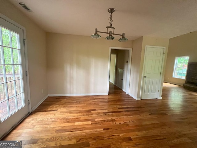 unfurnished dining area featuring a healthy amount of sunlight, baseboards, and wood finished floors