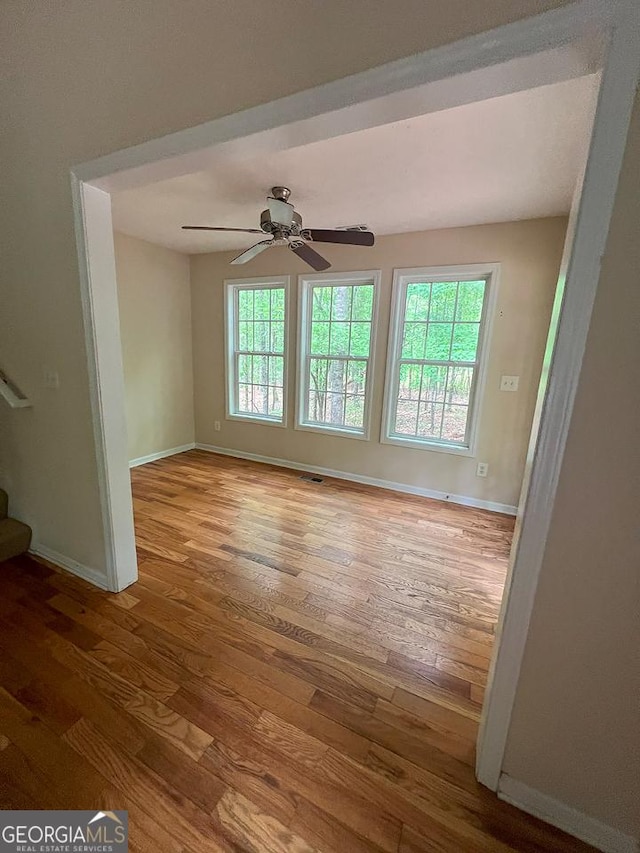 spare room featuring a ceiling fan, baseboards, stairway, and hardwood / wood-style floors