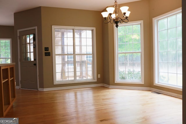 unfurnished dining area with a healthy amount of sunlight, baseboards, and wood finished floors