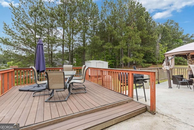 wooden terrace with outdoor dining area, an outdoor structure, a shed, and a gazebo