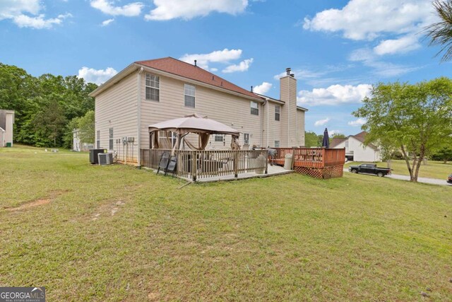 back of property featuring a gazebo, a wooden deck, central AC unit, a chimney, and a lawn