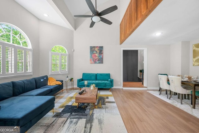 living room featuring a healthy amount of sunlight, high vaulted ceiling, ceiling fan, and baseboards