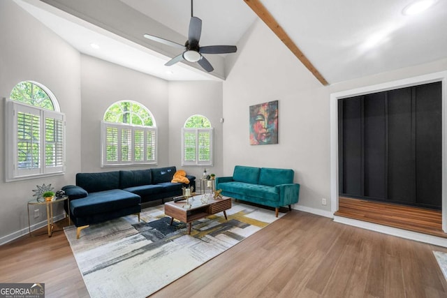 living room featuring ceiling fan, wood finished floors, high vaulted ceiling, baseboards, and beamed ceiling