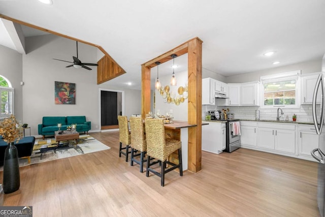 kitchen featuring stainless steel electric stove, a healthy amount of sunlight, a ceiling fan, and open floor plan