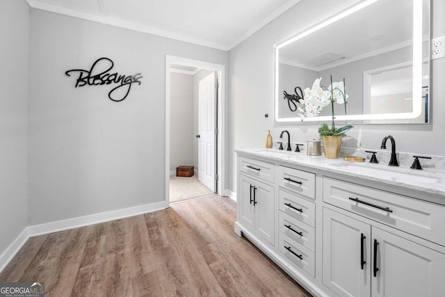 bar featuring a sink, baseboards, ornamental molding, and light wood-style floors