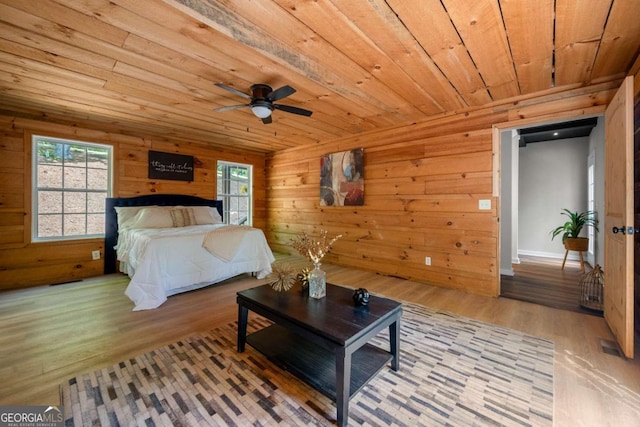 bedroom featuring wooden walls, multiple windows, wooden ceiling, and light wood finished floors