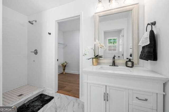 bathroom featuring a tile shower, marble finish floor, and vanity