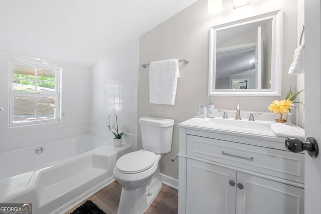 full bath with wood finished floors, a bathing tub, baseboards, vanity, and toilet